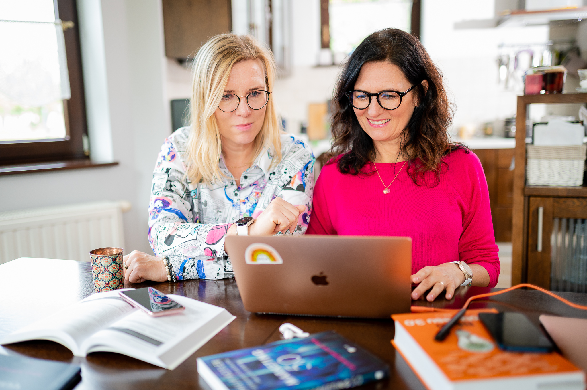 dwie kobiety siedzą przy stole i pracują nad nową stroną internetową roznestrony.pl